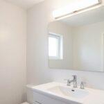 Duże lustro w małej łazience odbijające światło i optycznie powiększające przestrzeń