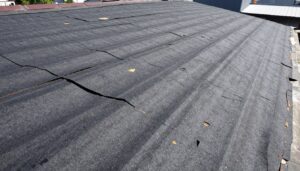 Zniszczona papa na dachu płaskim pokazująca pęknięcia i uszkodzenia