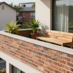 Murek zamiast balustrady na nowoczesnym balkonie z siedziskiem i roślinami