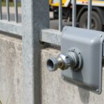 Przyłącze szamba w ogrodzeniu z widoczną szybkozłączką umożliwiającą podłączenie wozu asenizacyjnego